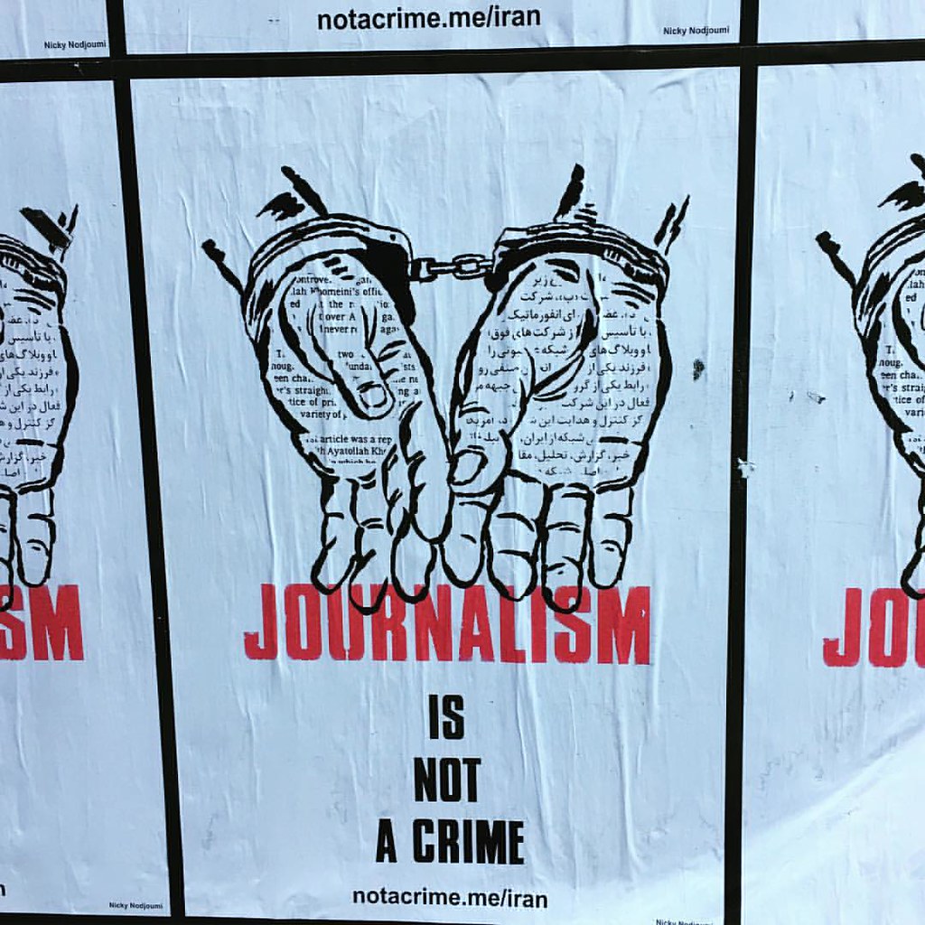 A poster showing handcuffed wrists with the caption "Journalism is not a crime."