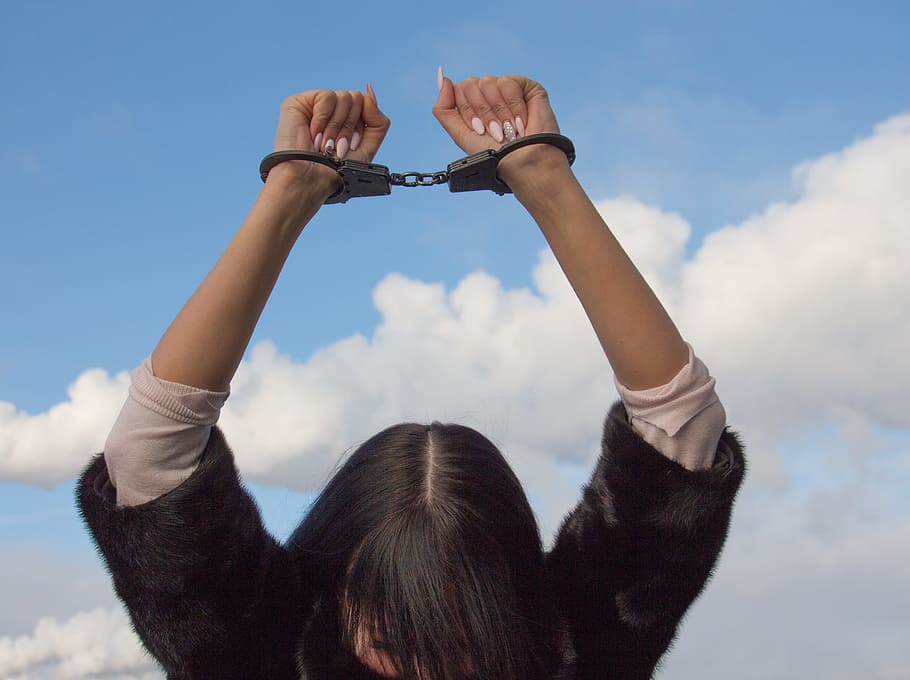 A woman holds handcuffed wrists into the sky