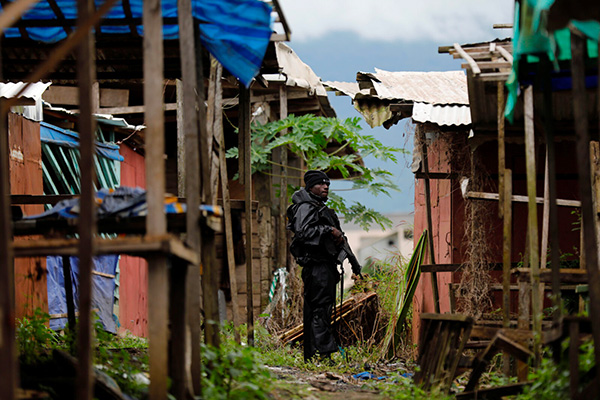 An armed man stands between makeshift homes in Cameroon