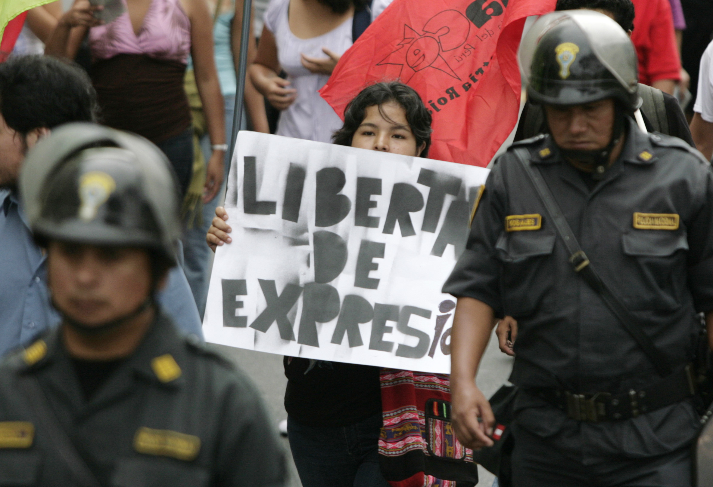 A Peruvian indigenous protestor holds a banner that reads 'Freedom of Expression' in Spanish during a march in Lima