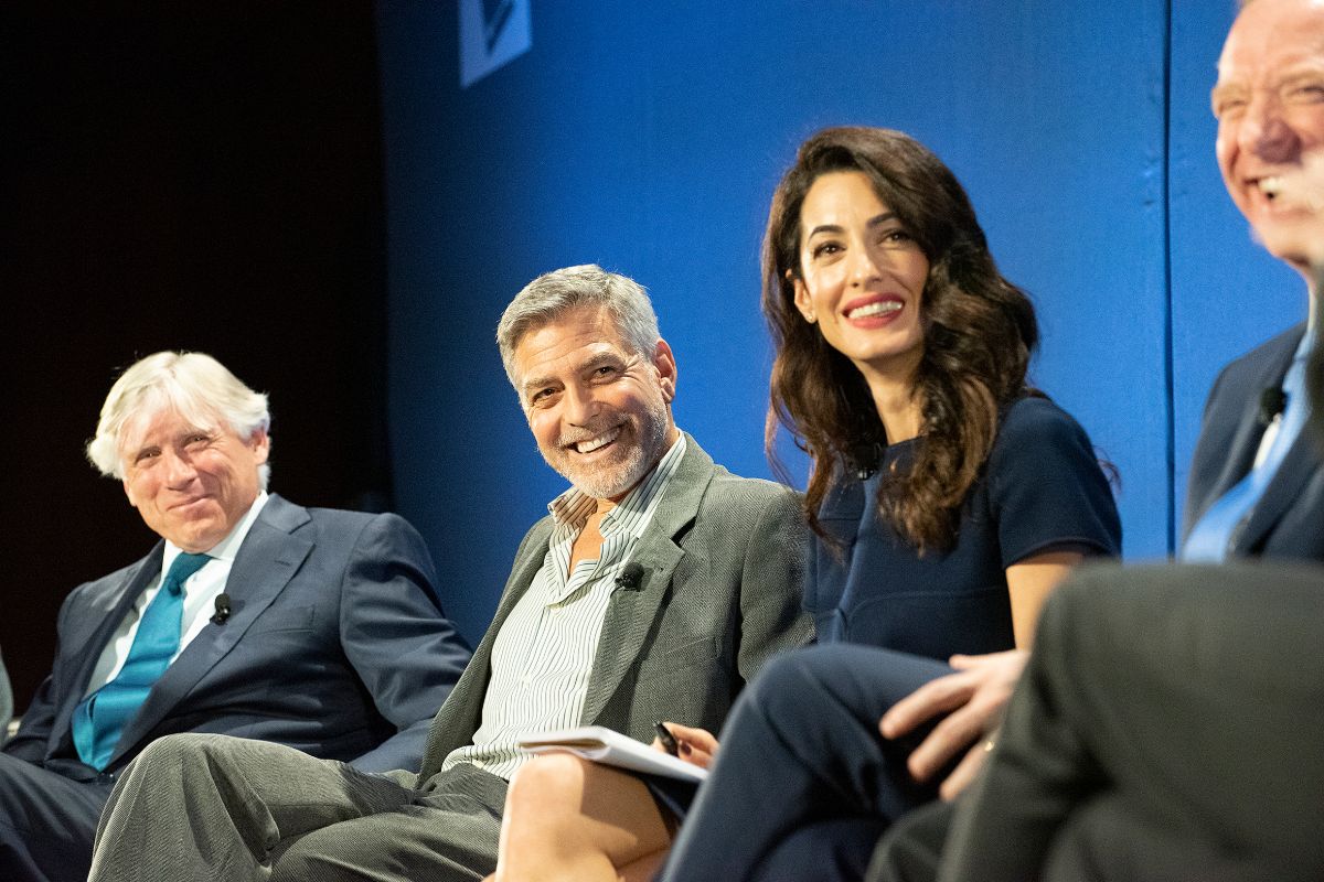 George and Amal Clooney smile with other participants in a panel at the TrialWatch conference