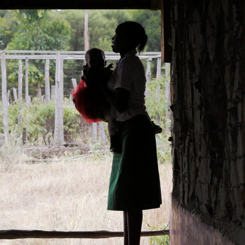 A teenage mother carries her child outside a class in Kenya