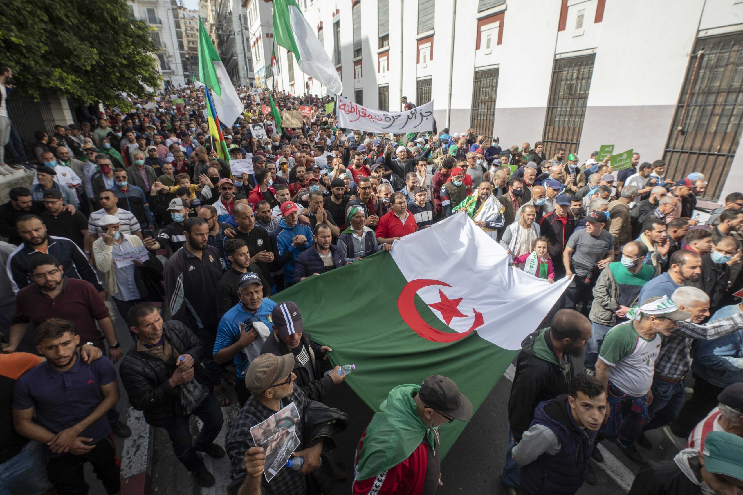 Protesters in Algeria raise their country's flags and a banner reading 'Free and Democratic Algeria'