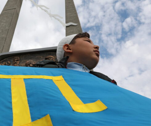 A participant holds a Crimean Tatars flag during a rally marking the anniversary of the mass deportation of Crimean Tatars from the region
