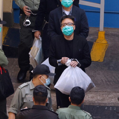 Pro-democracy activist Tam Tak-chi walks to a prison van to head to court