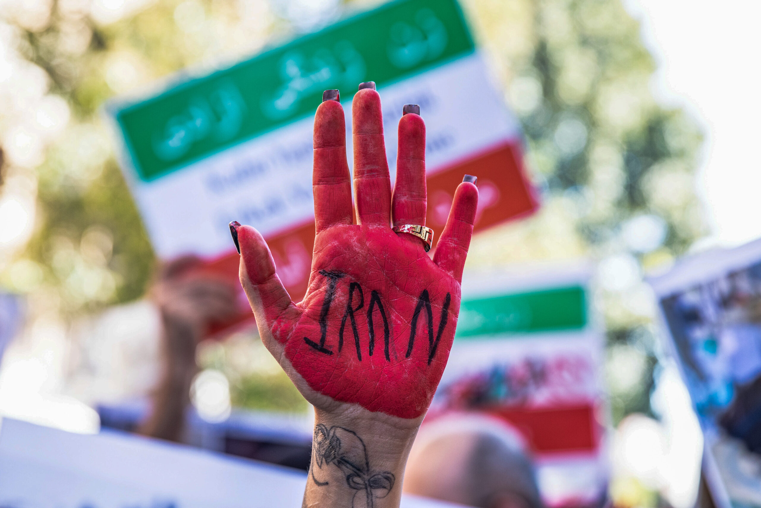 A protester with red painted hands and inscription "Iran" takes part outside the Iranian Consulate during the demonstration.