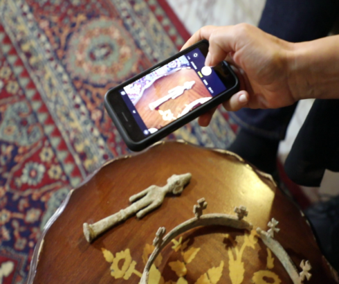 Someone takes a photograph of ancient antiquities laid on a table