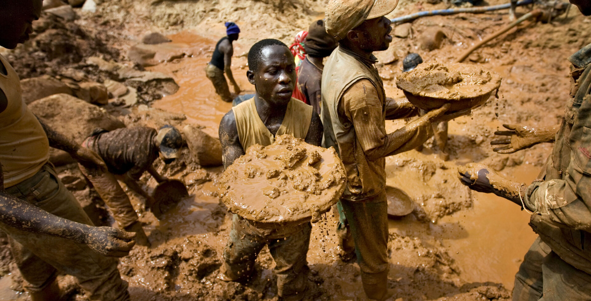 Gold miners form a human chain while digging an open pit