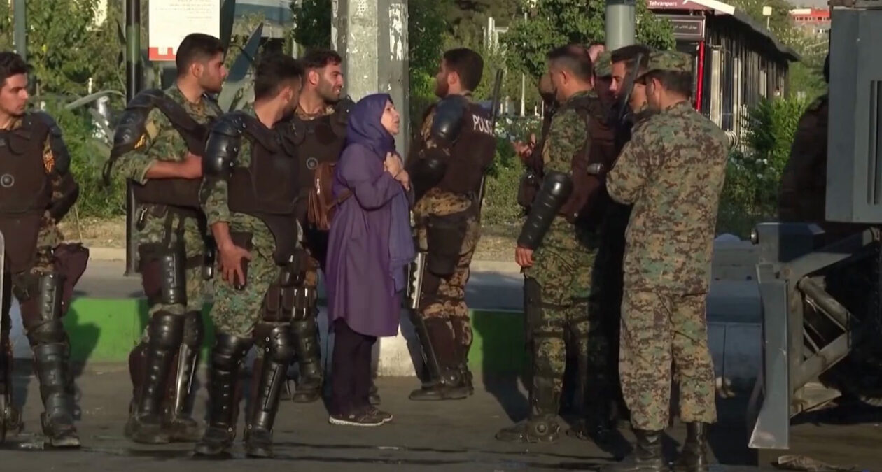 A woman surrounded by armed security forces in Iran