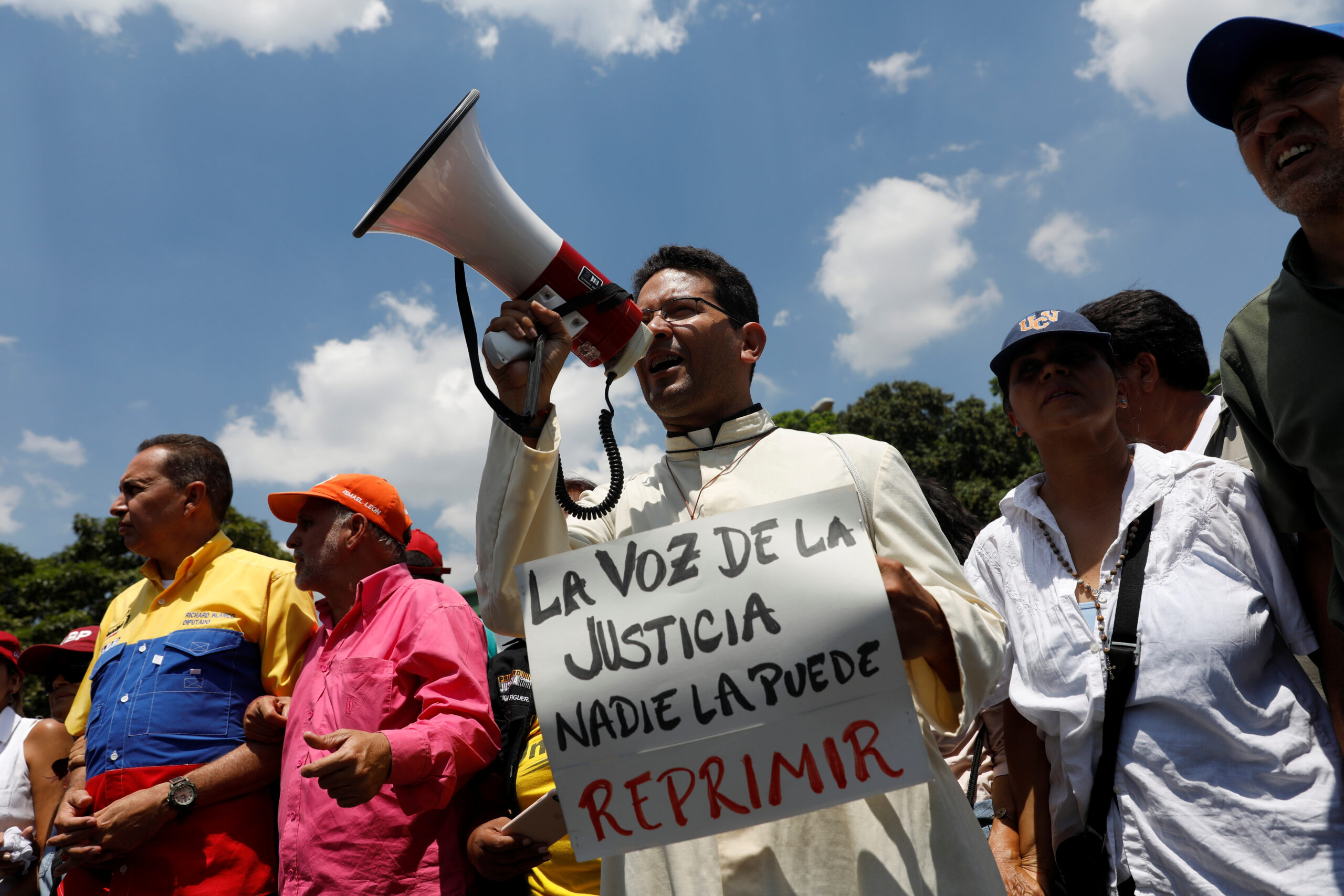A priest uses a megaphone while holding a sign that reads 'Nobody can repress the voice of justice' in Spanish during a rally against Venezuela's President Nicolas Maduro in Caracas, Venezuela