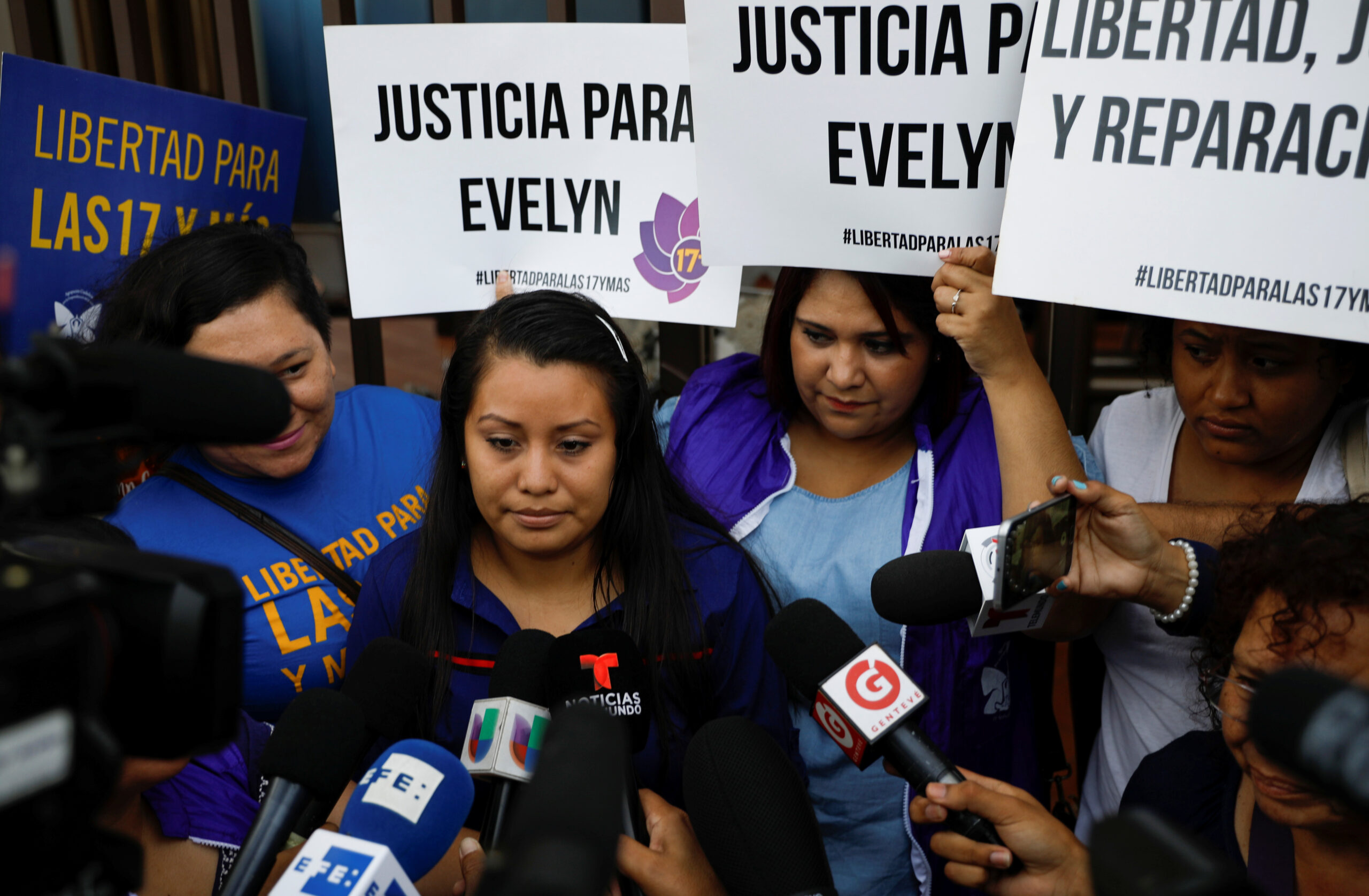Evelyn Hernandez speaks to the media as she arrives for a hearing in El Salvador. Placards read "Justice for Evelyn". (REUTERS/Jose Cabezas)