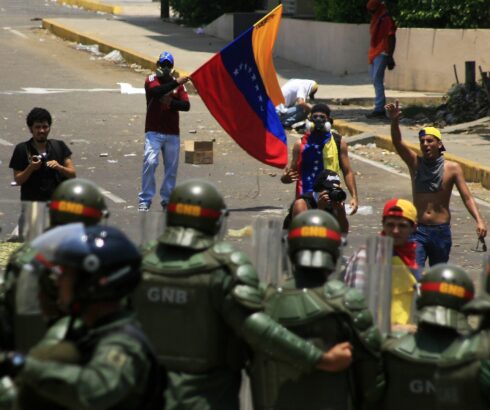 Protesters in Venezuela carry their country's flags and approach security forces