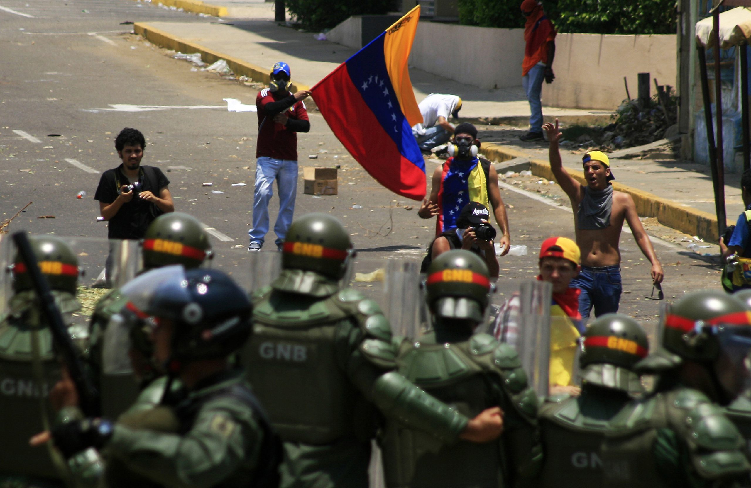 Protesters in Venezuela carry their country's flags and approach security forces