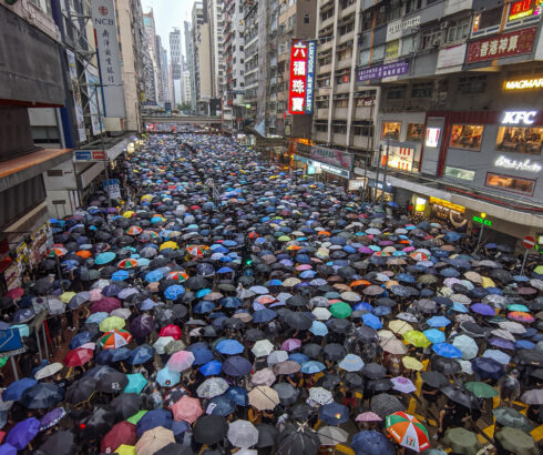 Hundreds of protesters in Hon Kong hold umbrellas as they stand under the rain