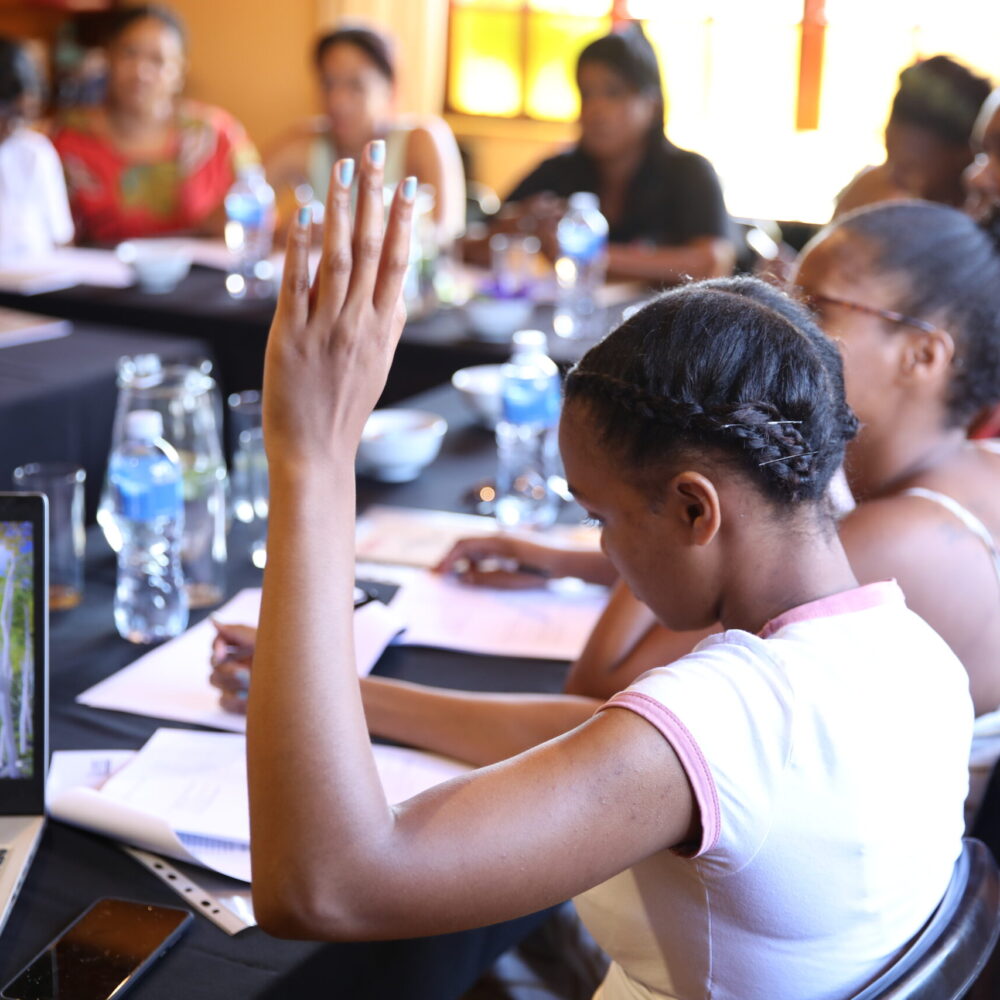 A girl raises her hand during a workshop with others