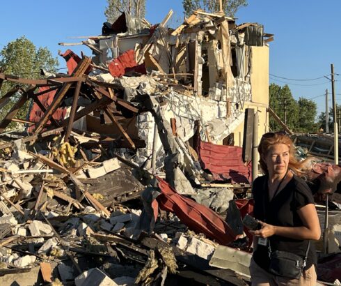 The Legal Director of the Clooney Foundation for Justice's Docket initiative standing near a destroyed building in Ukraine