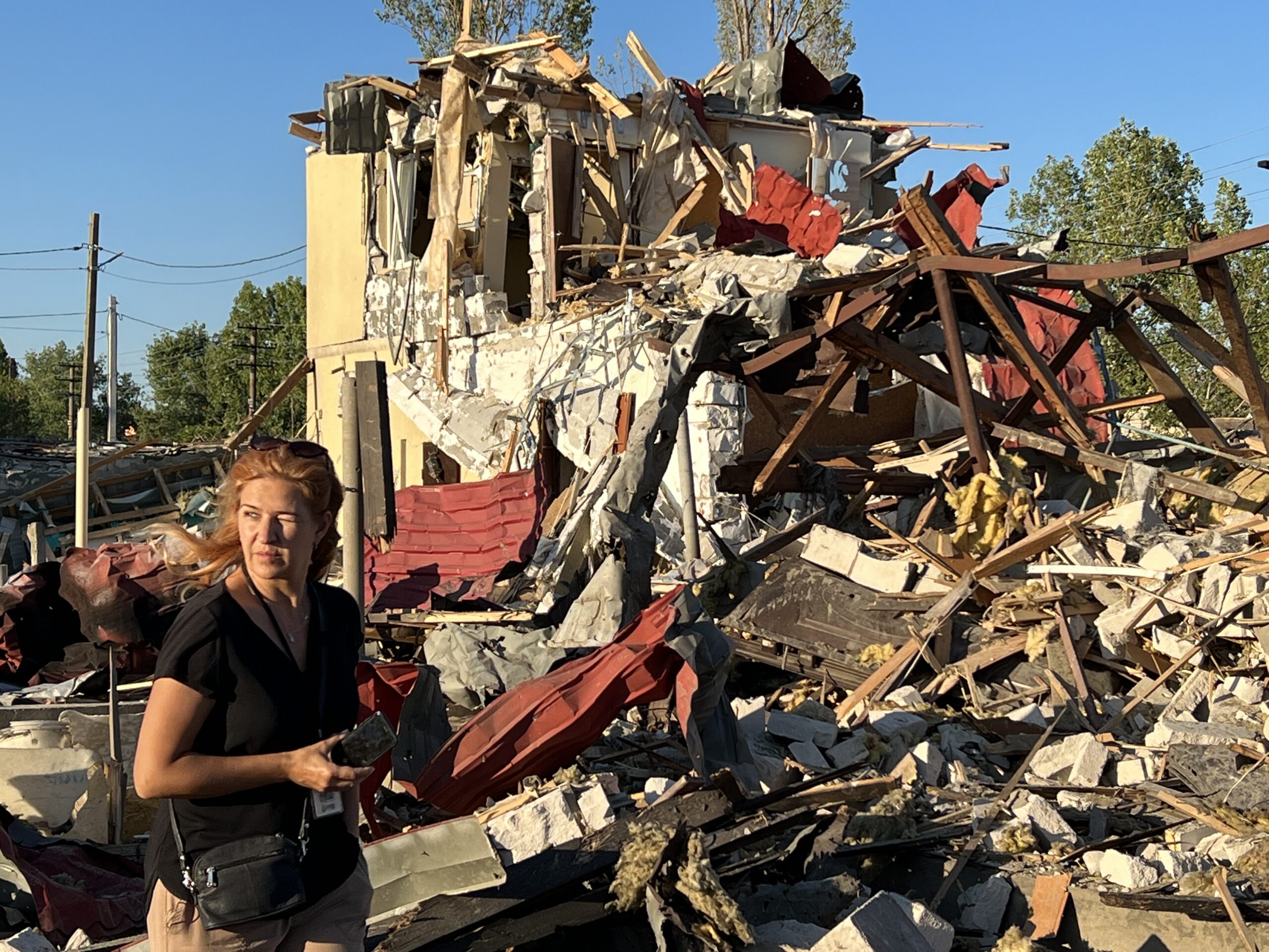 The Legal Director of the Clooney Foundation for Justice's Docket initiative standing near a destroyed building in Ukraine